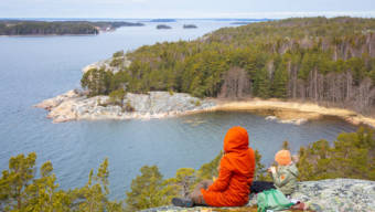 Retkeilijät kalliolla ihailemassa saaristomaisemaa.