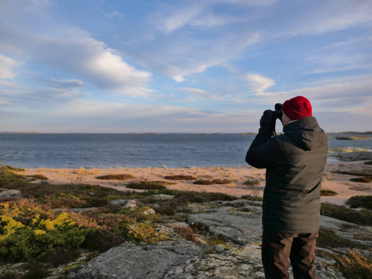 En man ser på havslandskap med kikare i Vänö. 